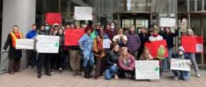 Group photo of diverse people holding signs and dressed in Christmas colors.