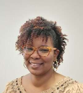 Picture of Patrice, a Black woman with glasses and large gold hoop earrings smiling.