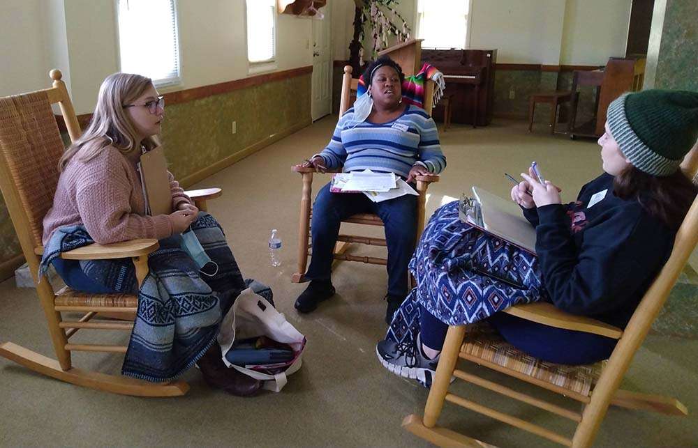 2 white and 1 Black woman sitting together in rocking chairs