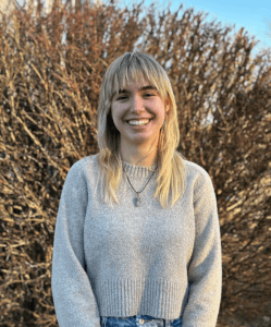 Picture of a young white woman standing in front of a grassy background